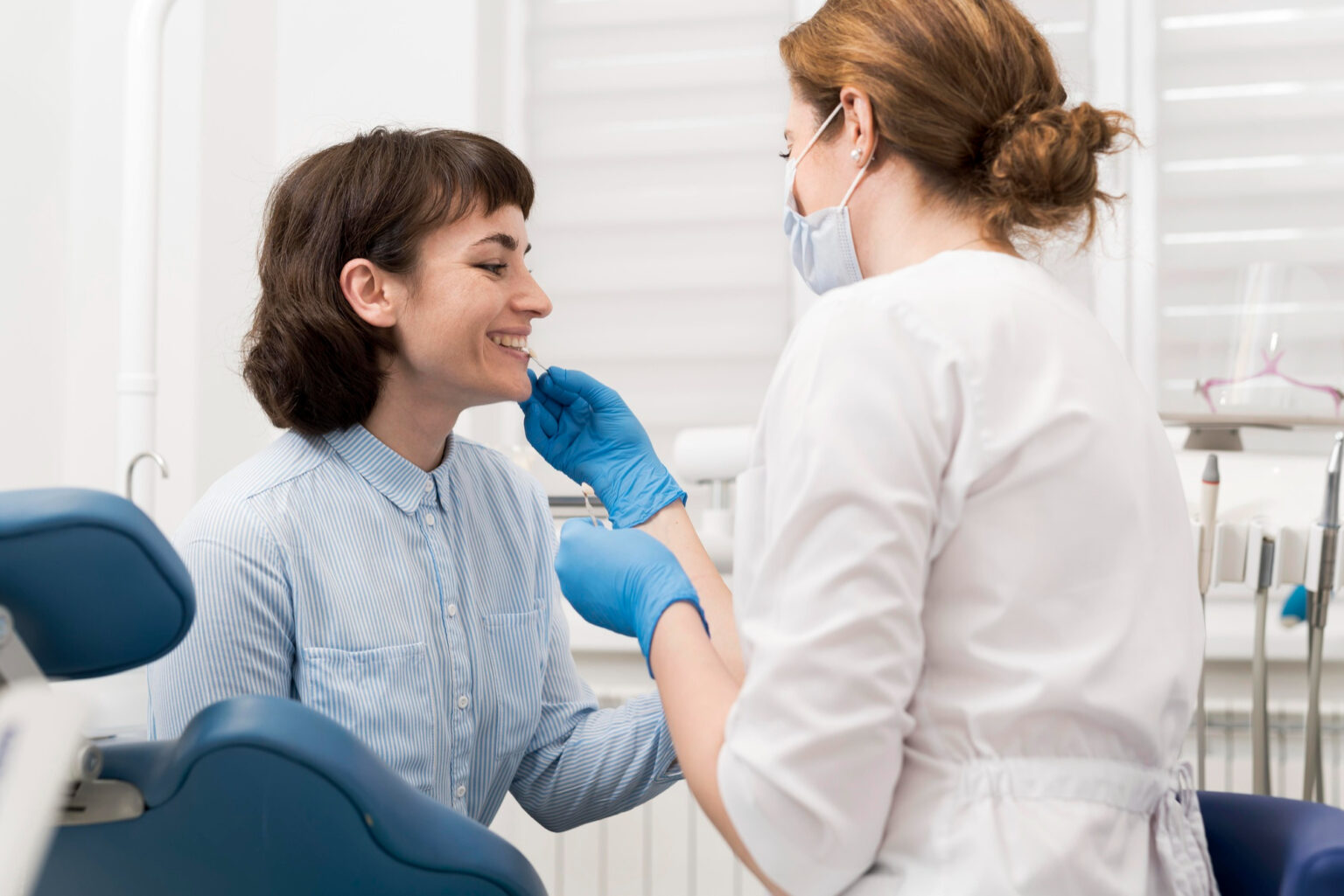 A smiling female patient receives attention from a dental professional