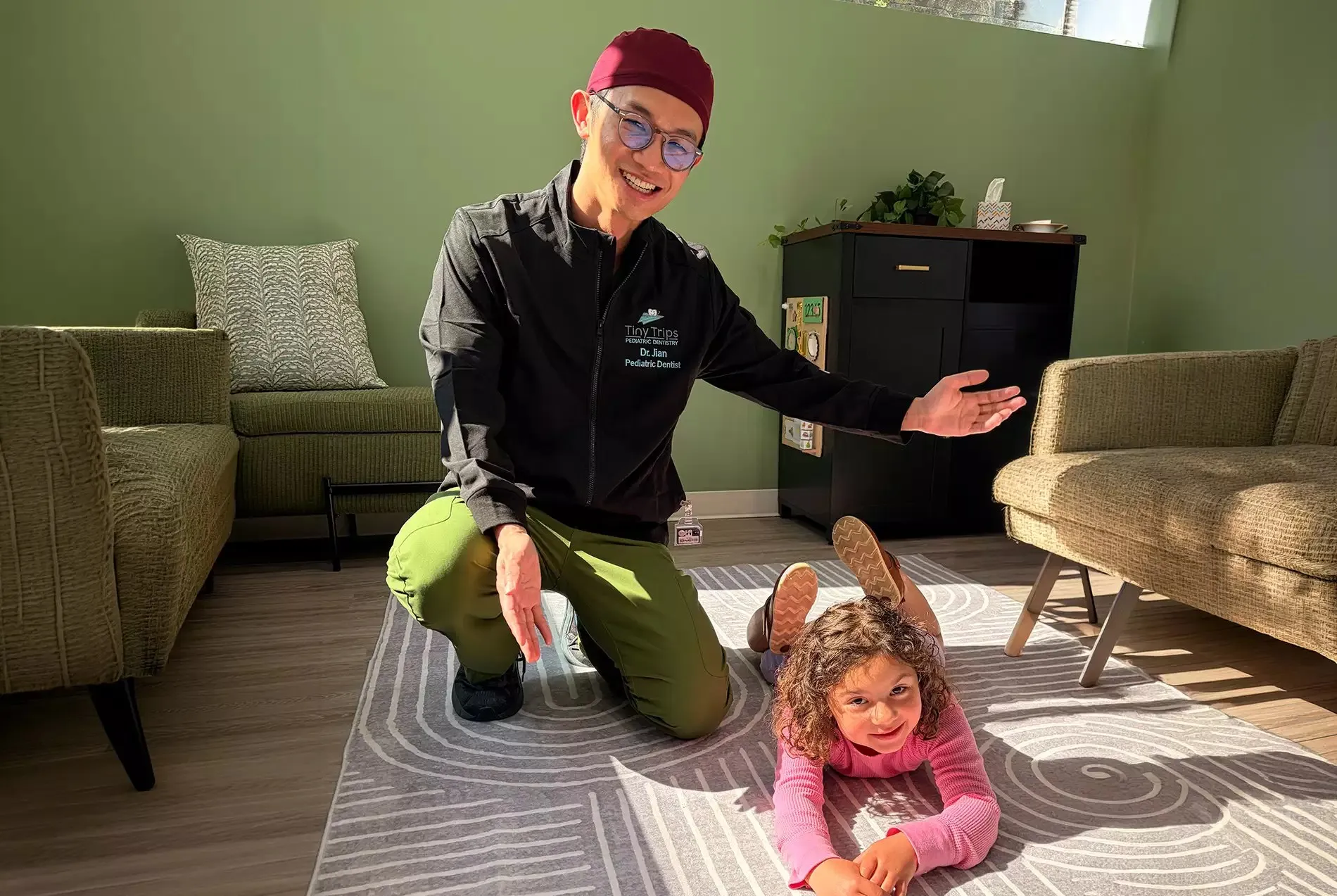 Dr. Lee playing with a young patient in the waiting area