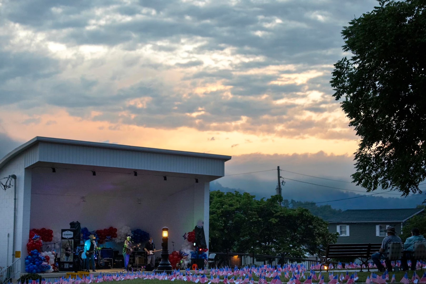 A band performing at dusk with American flags in the foreground