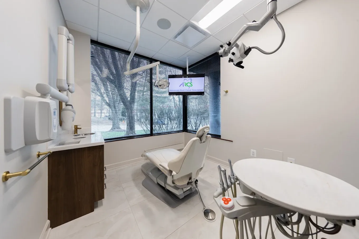 Stylish accessible restroom featuring dramatic blue-veined marble tile flooring, a navy accent wall, gold fixtures, a floating white sink, and a modern geometric chandelier.